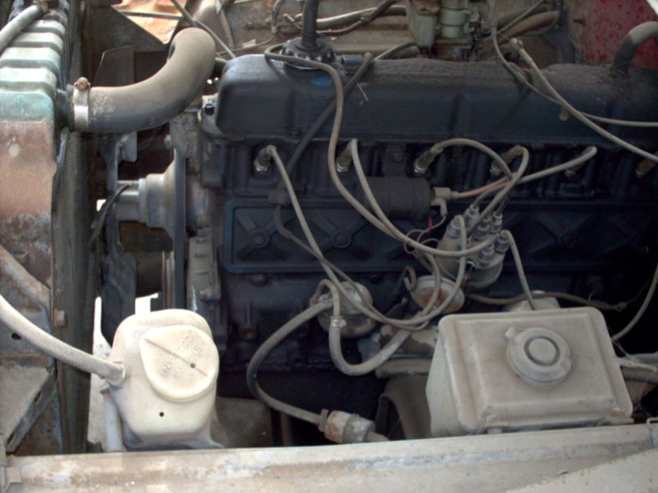 Engine bay with radiator, hoses, and engine block visible. Includes a white plastic fluid reservoir