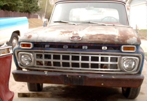1965 Ford F-100 - Front view of a weathered 1965 Ford F-100 pickup truck with a prominent grille and Ford badging.