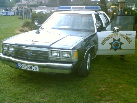 1991 Ford Crown Victoria - This 1991 Ford Crown Victoria police car is parked on grass with a trooper standing by the open door.