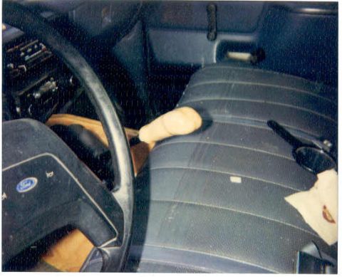 1989 Ford Bronco - The interior of a vehicle is shown, focusing on the shifter knob resting on the seat next to the steering wheel.