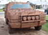1990 Ford Bronco - This 1990 Ford Bronco is heavily covered in mud, obscuring its original appearance but retaining its iconic front-end features.