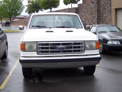 1983 Ford Bronco - A white Ford F-Series truck is parked in a lot, showing its front grille and hood details.