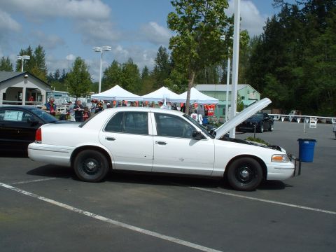 1999 Ford Crown Victoria - White Ford Crown Victoria with hood open at an outdoor event, another car visible behind.
