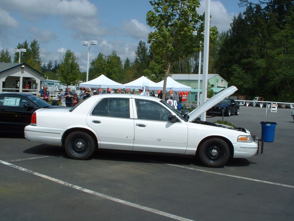 White Ford Crown Victoria parked outside with hood open, black car behind it