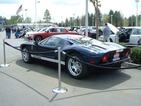 1999 Ford Crown Victoria - Dark blue Ford GT sports car with white racing stripes on display at an outdoor event.