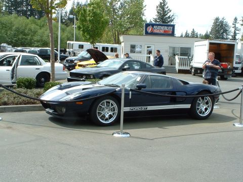 1999 Ford Crown Victoria - A dark blue Ford GT is displayed with stanchions in front of a building with trailers for sale.