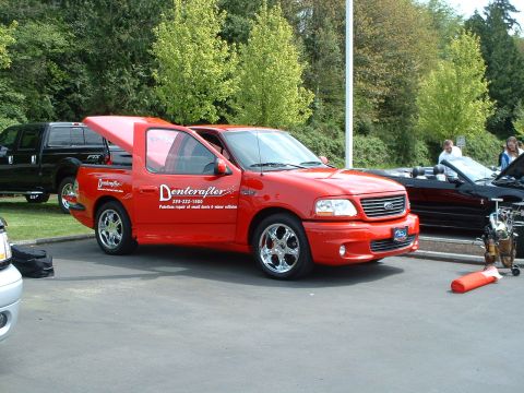 1999 Ford Crown Victoria - A red 1999 Ford F-150 SVT Lightning pickup truck is shown with custom "Denterafter" graphics and a unique bed cap.