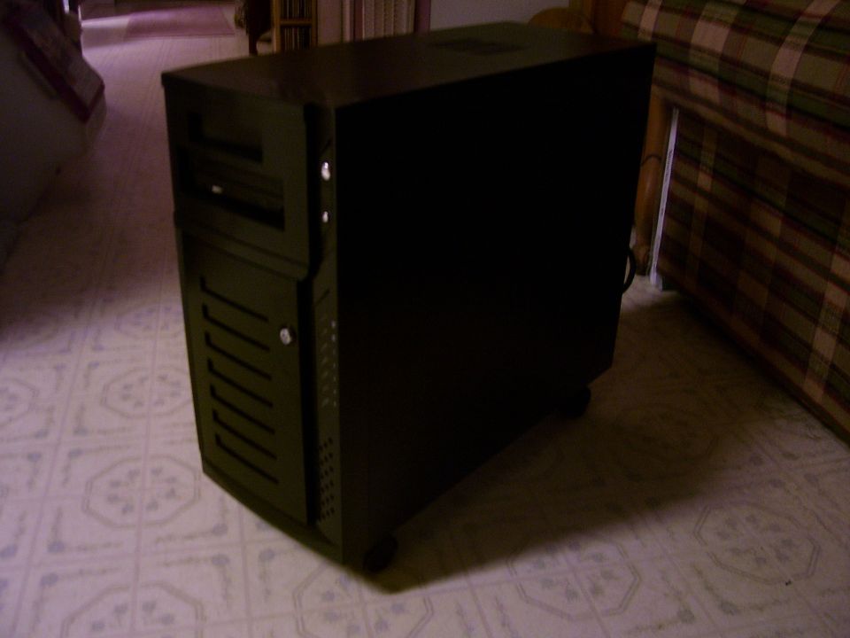 Black computer tower case on patterned floor by plaid furniture