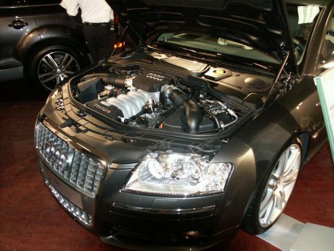 2001 Mercury Grand Marquis - The front of a dark grey Audi S8 is visible, with its hood open to reveal the engine compartment.