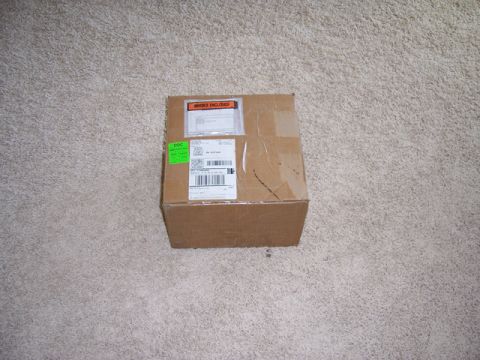 1996 Ford Bronco - A cardboard box sits on a carpeted floor, covered in shipping labels and an invoice sticker.