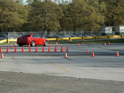2001 Mercury Grand Marquis - A red sedan drives through a course marked by orange traffic cones on a paved lot.