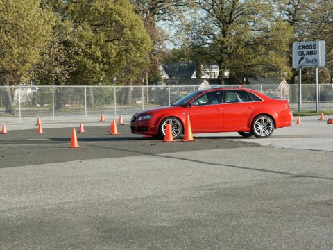 2001 Mercury Grand Marquis - A red sedan drives through a cone course, with a sign for Cross Island South in the background.