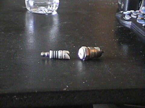 1994 Ford Bronco - Two spark plugs are shown on a table, one of them is broken.