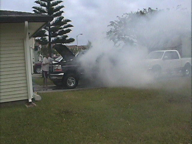 Black 1994 Ford Bronco billowing smoke with hood open