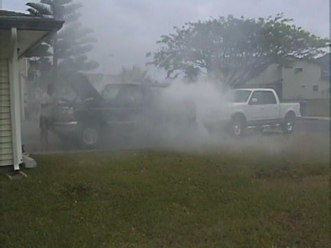 1994 Ford Bronco - Two trucks are visible, one is dark and has its hood open, emitting a large amount of smoke.