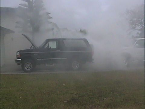 1994 Ford Bronco - A Ford Bronco is engulfed in smoke, with its hood open, suggesting a mechanical issue.