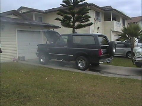 1994 Ford Bronco - Black 1994 Ford Bronco with hood open, parked in front of a house. Another vehicle is parked nearby.