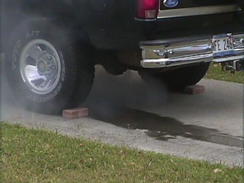 1994 Ford Bronco - Black Ford Bronco rear view shows smoke from exhaust and a license plate reading MFE 246.