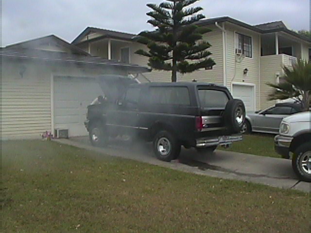 Black 1994 Ford Bronco with hood open and smoke billowing out