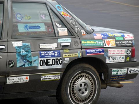 1988 Ford E250 - This car displays numerous stickers with various messages, obscuring its make and model.
