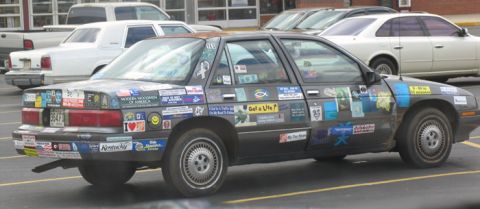 1988 Ford E250 - A heavily stickered sedan is parked in a lot, with other vehicles nearby.