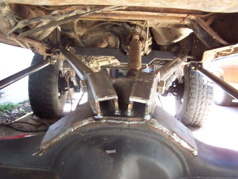 1987 Ford Bronco - Custom suspension components are visible underneath a vehicle, focusing on the rear axle and linkage system.