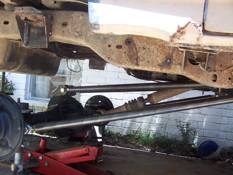 1987 Ford Bronco - The underside of a vehicle shows extensive modifications to the suspension system, including new linkage and a lifted axle.