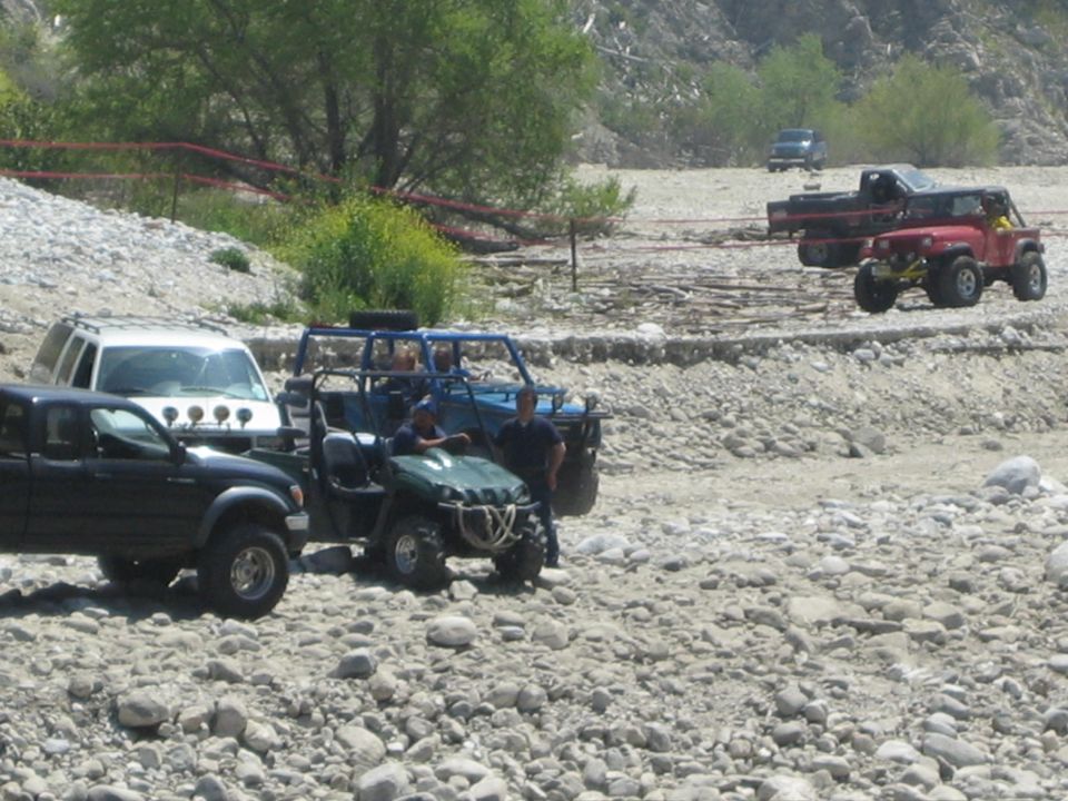 Several off-road vehicles parked on a rocky, dry riverbed