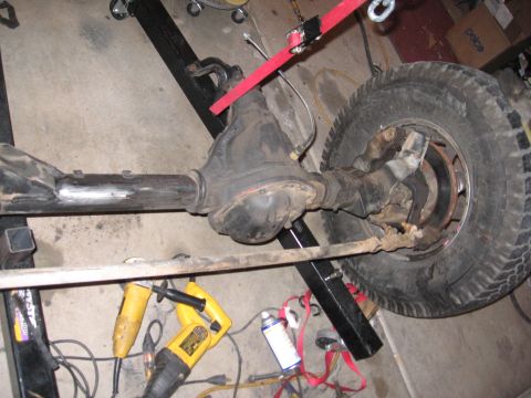 1990 Ford Bronco - The photo shows a vehicle's axle and suspension parts, with tools and straps suggesting maintenance or modification.