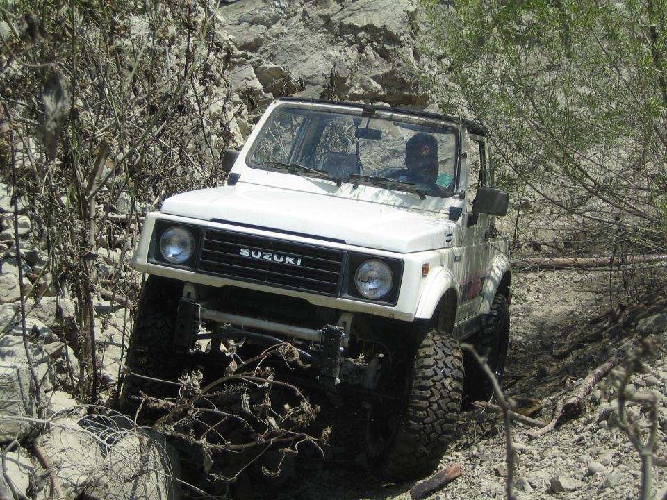 White 1987 Suzuki Samurai navigating a rocky off-road trail