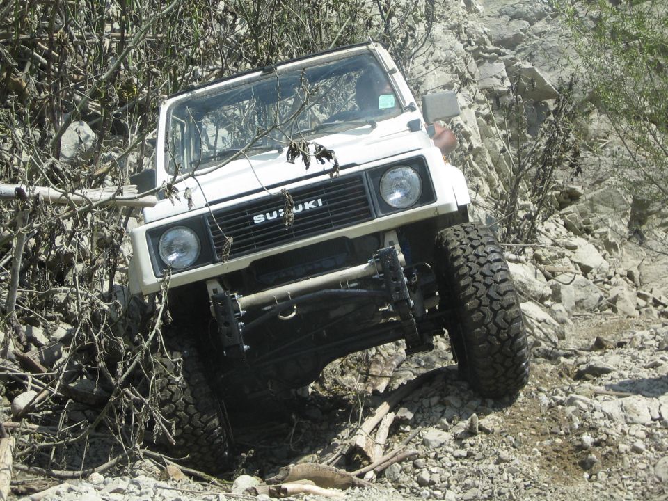 White 1987 Suzuki Samurai navigating a rocky incline