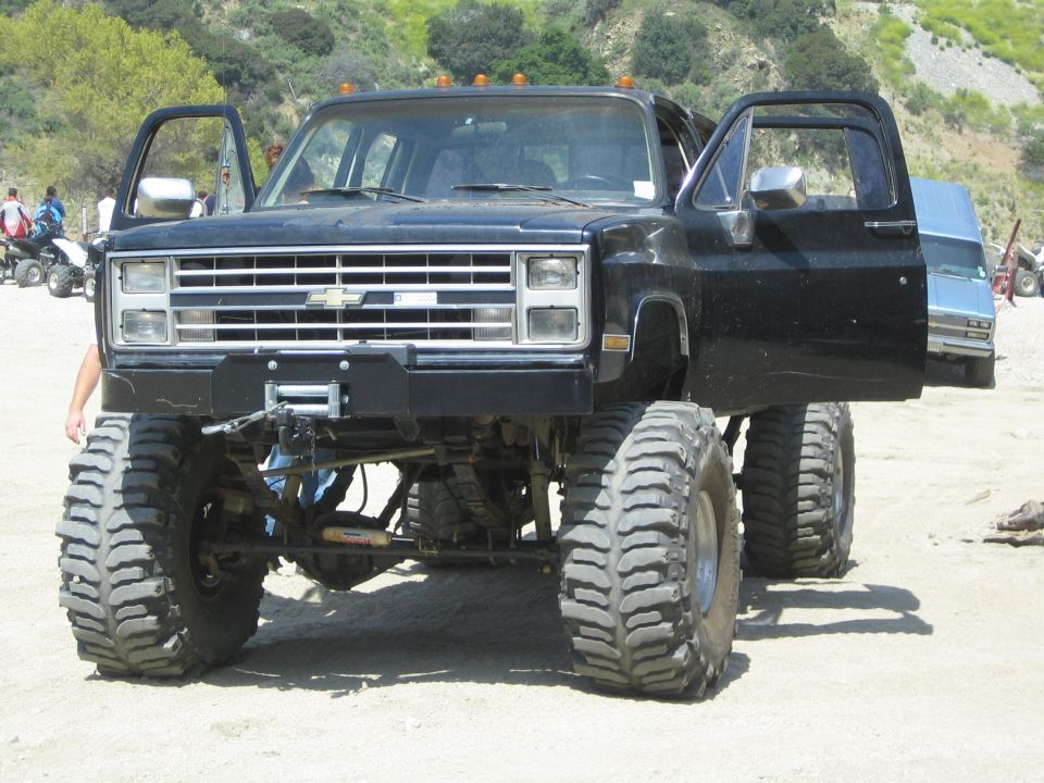 Lifted black Chevrolet pickup truck with doors open, large off-road tires, and a winch