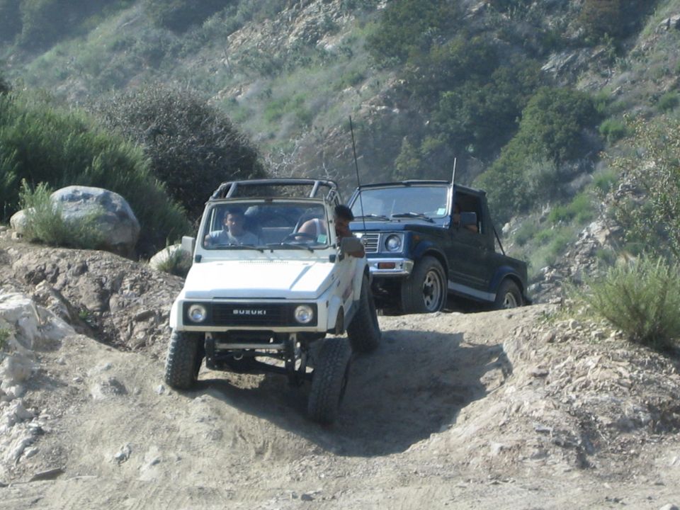 White 1987 Suzuki Samurai leads blue 1987 Suzuki Samurai off-road