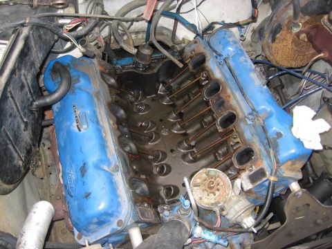 1979 Ford Bronco - Close-up view of an engine with blue valve covers removed, revealing the internal components like lifters and pushrods.