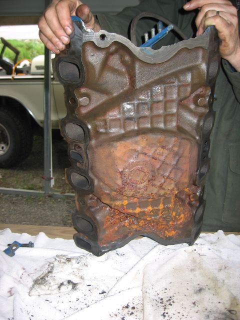 1979 Ford Bronco - Heavily rusted engine cylinder head being held up for inspection.