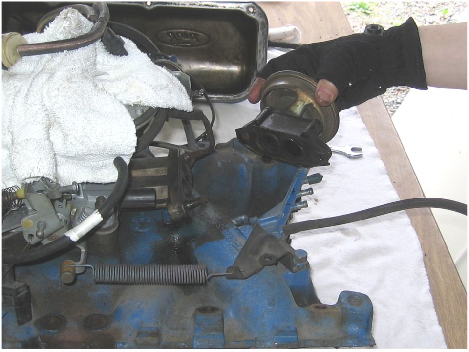 Blue engine block with carburetor and a hand holding a vacuum actuator
