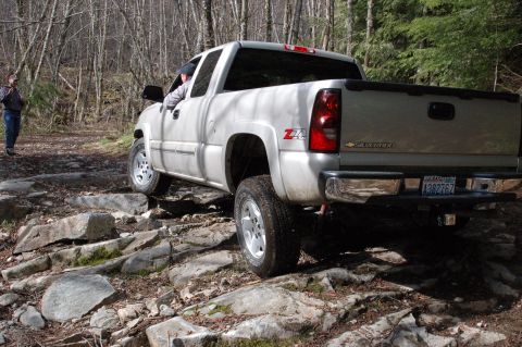2006 Ford F-250 - Silver Chevrolet Silverado Z71 navigates a rocky path in a wooded area.