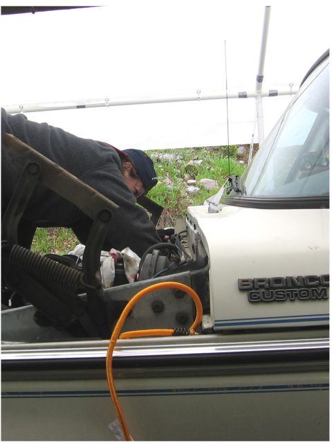 1979 Ford Bronco - A person is working on the engine of a white Ford Bronco Custom.