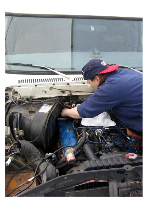1979 Ford Bronco - A person works on the engine of a white 1979 Ford Bronco.
