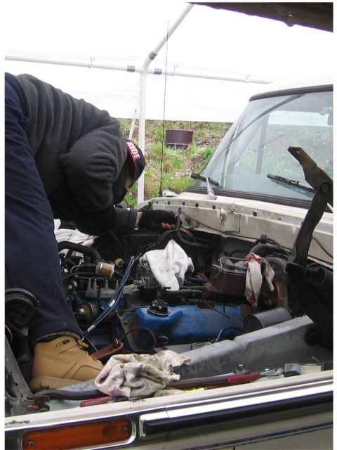 1979 Ford Bronco - Mechanic working on the engine of a 1979 Ford Bronco under a canopy.