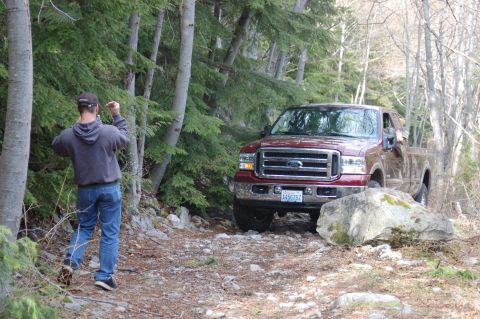 2006 Ford F-250 - Ford Super Duty truck on a rough, wooded path. The grille indicates a model year around 2005.
