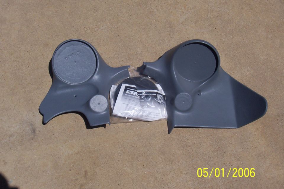 Gray plastic console trim panel with cup holders and an instruction sheet in a bag, on concrete.