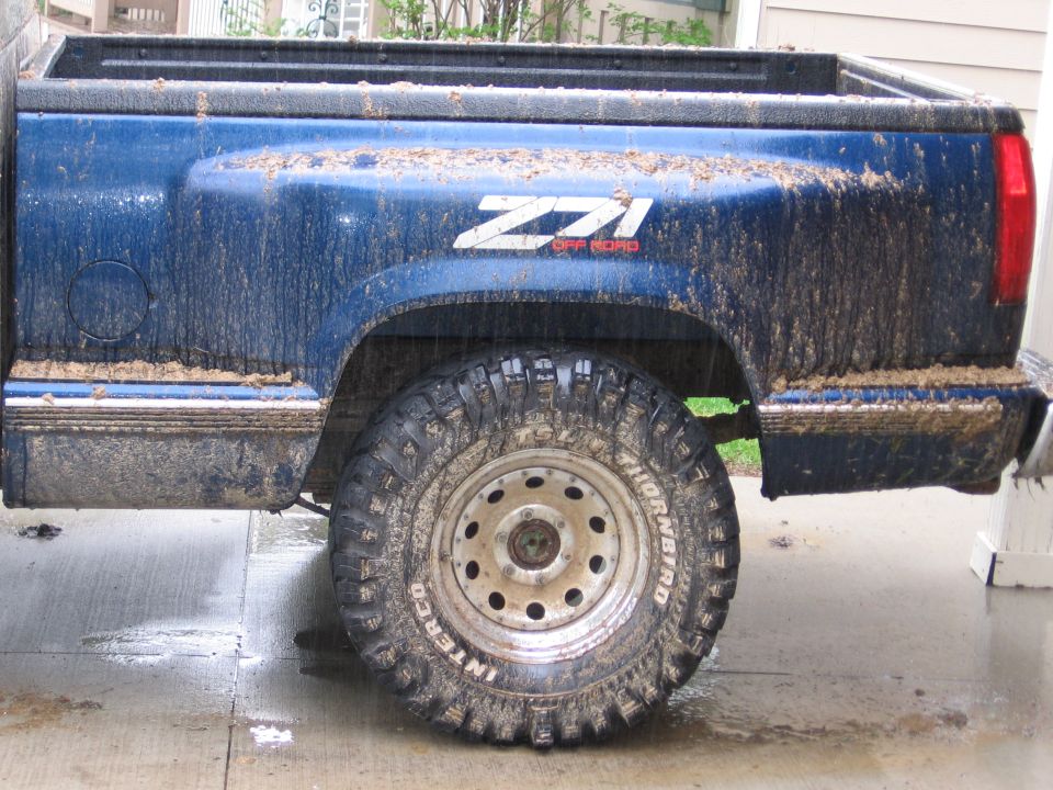 Side view of a muddy blue 1995 GMC Sierra 1500 Z71 pickup truck with off-road tires