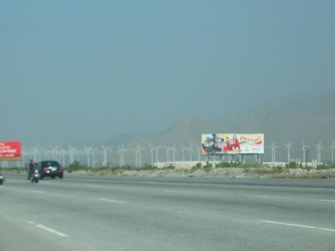 1991 Ford Bronco - A billboard advertising Mexicali is visible alongside a highway, with a field of wind turbines in the distance.