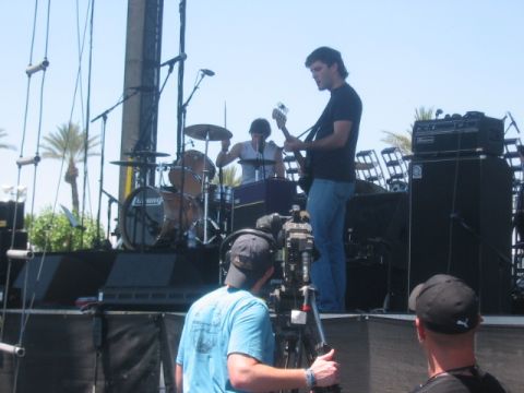 1991 Ford Bronco - A band plays on an outdoor stage, with a cameraman filming the performance.