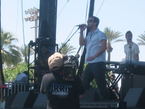 1991 Ford Bronco - A band performs live on an outdoor stage, with a cameraman capturing the event.