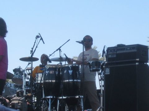 1991 Ford Bronco - A band performs on stage with a drummer and conga player visible under a bright sky.