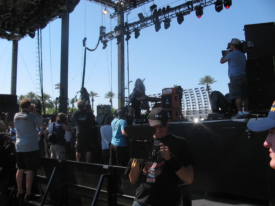 Stage setup with palm trees and a crowd watching a performance