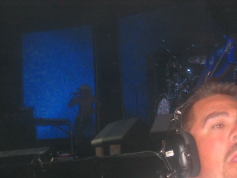 1991 Ford Bronco - A performer is silhouetted against a blue screen on a stage, with a drum kit visible to the right.