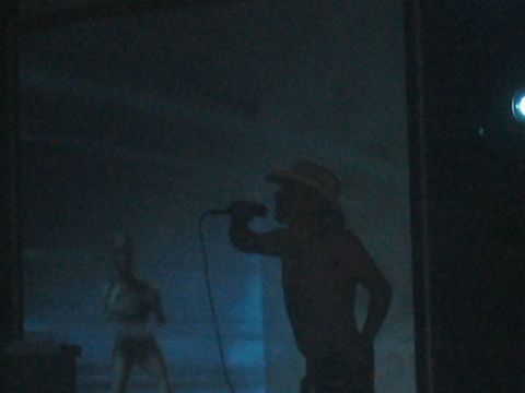 1991 Ford Bronco - A performer in a cowboy hat sings into a microphone, silhouetted against a blue background.